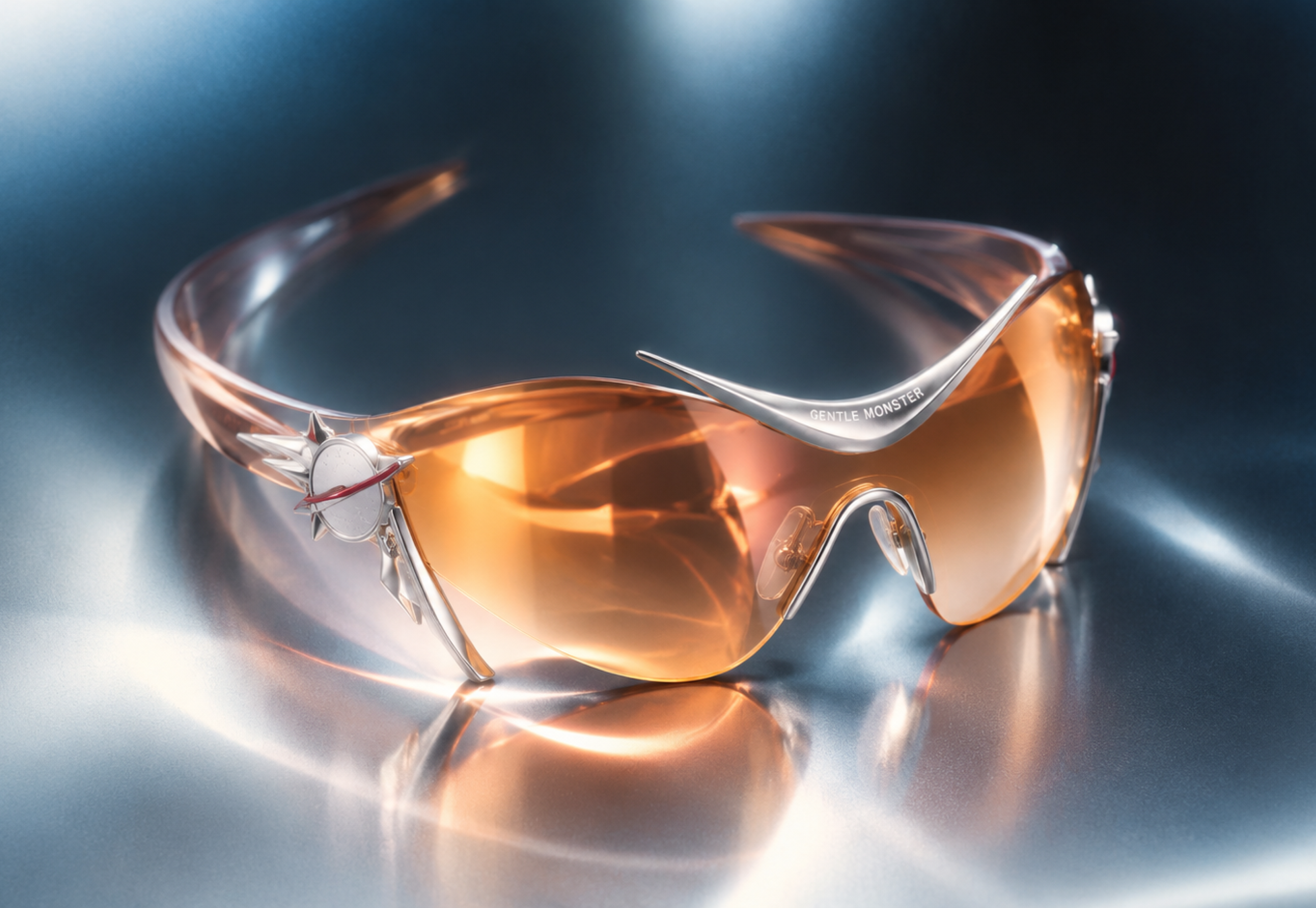 Gentle Moonster, chrome sunglasses with orange lenses on a pale blue ground