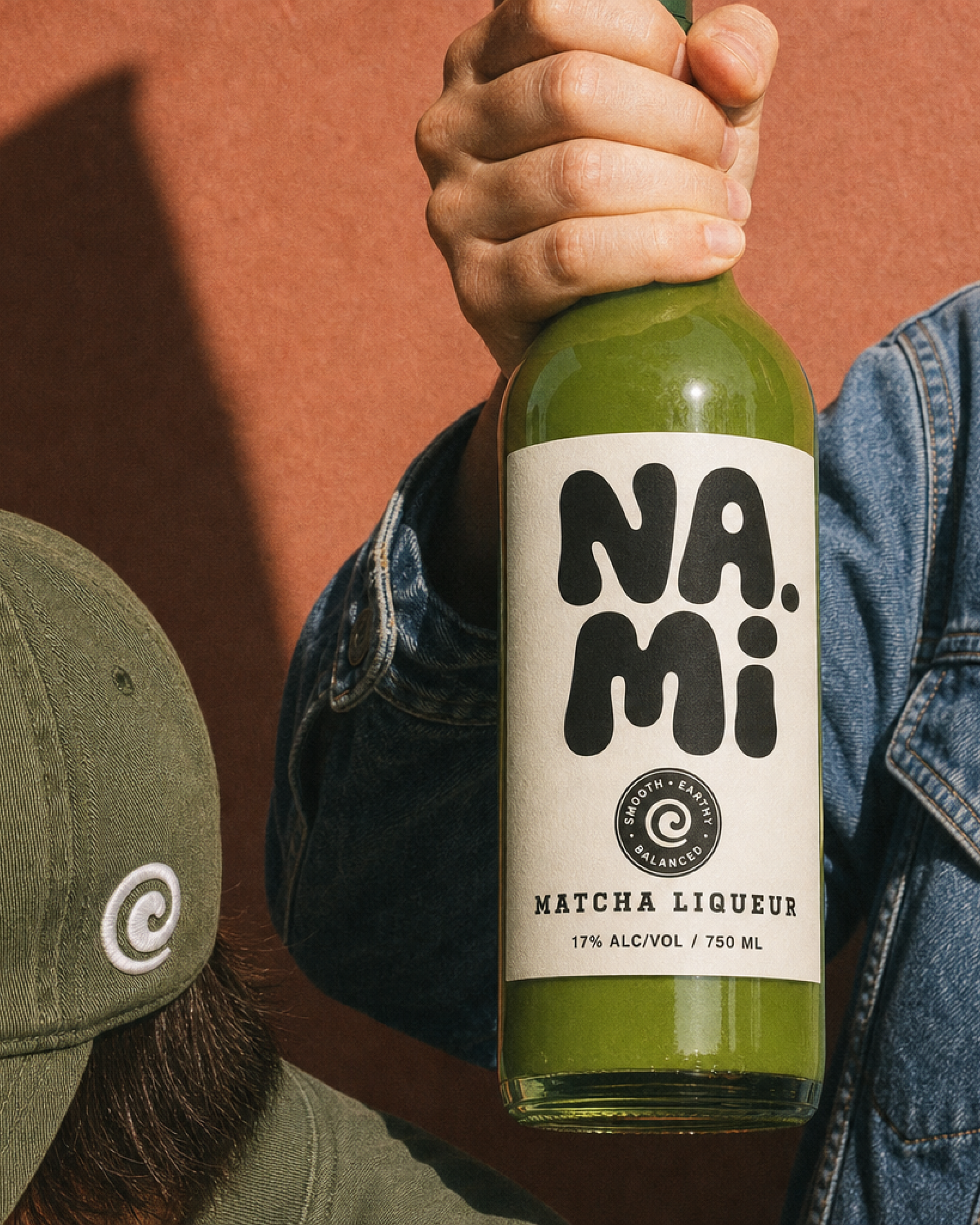 NAMI, a hand holding the bottle against a terracotta wall