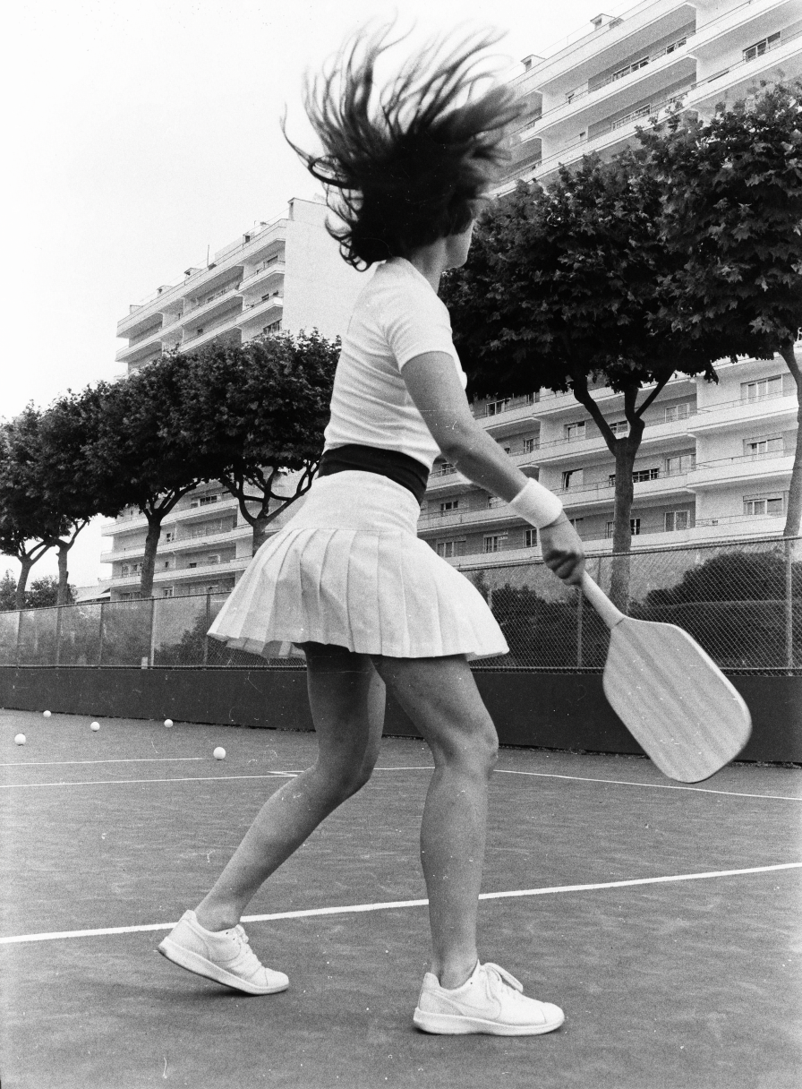 Picada, a black and white photo of a woman swinging a padel racket on court